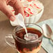 A person pouring Nestle Coffee-Mate into a cup of coffee.