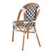 A Lancaster Table & Seating black and white rattan outdoor side chair with a woven back.