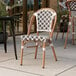 A Lancaster Table & Seating Bistro Series black and white birdseye weave rattan outdoor side chair on a patio.