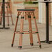 A Lancaster Table & Seating black Teslin outdoor backless barstool with black straps.