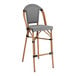 A Lancaster Table & Seating black and white outdoor side barstool with a Teslin seat and wooden legs.