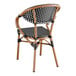 A Lancaster Table & Seating black and white checkered rattan arm chair.