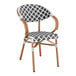 A Lancaster Table & Seating outdoor arm chair with a black and white woven rattan seat.