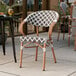 A Lancaster Table & Seating black and white rattan chair on a patio.