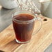 A glass cup of Nescafe Classico ground coffee on a wooden board.