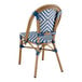 A close-up of a Lancaster Table & Seating navy and white chevron weave rattan side chair with a wooden frame.