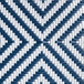 A close-up of a white woven rattan chair with a navy and white chevron pattern.