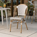 A Lancaster Table & Seating gray and white rattan outdoor side chair on a patio.