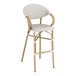 A white Lancaster Table & Seating outdoor arm barstool with wooden legs.