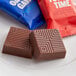 Two TCHO Oatally Awesome oat milk chocolate squares in blue wrappers on a plate.