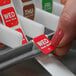 A person using a DayMark metal label dispenser to label a bottle on a hospital cafeteria counter.