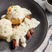A plate with two biscuits and Trio country gravy on it with a fork.
