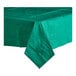 A folded green Table Mate tissue/poly table cover with a green napkin on a table.