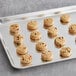 A tray of Otis Spunkmeyer Carnival cookies with multicolored sprinkles on a gray surface.