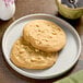 A plate of Otis Spunkmeyer White Chocolate Macadamia Nut cookies next to a cup of coffee.