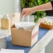 A hand holding a white Sabert Soup-N-Serve container in a box.