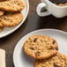 A plate of Otis Spunkmeyer Oatmeal Raisin cookies on a table with a cup of coffee.