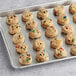 Preformed Otis Spunkmeyer Carnival Cookie with blue and yellow candy on a bakery tray.