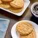 A plate of Otis Spunkmeyer peanut butter cookies on a table with a cup of coffee.