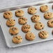 Preformed Otis Spunkmeyer whole grain chocolate chip cookie dough with chocolate chips on a baking sheet.