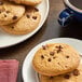 A plate of Otis Spunkmeyer whole grain chocolate chip cookies with a blue mug of coffee.