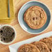 A plate of Otis Spunkmeyer chunky chocolate cookies next to a mug of coffee.