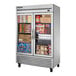 A True stainless steel glass door reach-in freezer full of food.