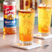 A pair of glasses with ice and orange Torani Sweet Heat-flavored liquid on a counter.