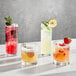 A group of Della Luce Origins double old fashioned glasses with different colored drinks and garnish on a table.