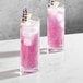 Two Della Luce Origins beverage glasses with pink drinks and ice cubes.