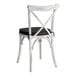 A Lancaster Table & Seating Vineyard Series white outdoor cross back chair with a black cushion.