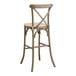 A Lancaster Table & Seating Vineyard Series whiskey brown outdoor cross back bar stool with a Chardonnay tan linen cushion.