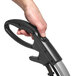 A hand holding a black and silver Tornado upright vacuum cleaner.