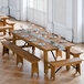 A Lancaster Table & Seating Vineyard Series outdoor table with benches set up on a wooden floor with plates and glasses on it.