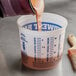 A liquid being poured into a Midwest Rake multi-purpose mixing container.