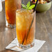 A glass of Jones Iced Tea with a straw and a mint leaf.