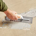 A person using a Midwest Rake epoxy mortar trowel on a floor.