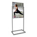 A woman stretching her leg using a Chrome Bulletin Sign Holder with rectangular tubing framed base.