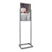 A woman holding a sign with a woman's face on it in a chrome bulletin sign holder.