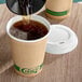 A person pouring brown coffee into an EcoChoice Kraft paper hot cup.