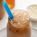 A glass jar with a straw filled with brown Bossen Original Crystal Boba and ice.