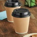 Two brown paper cups with black lids.