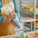 A person decorating a cupcake with a blue pastry bag.