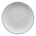 A white porcelain coupe plate with blue speckles and a blue rim.