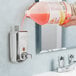 A hand pouring Novo antibacterial hand soap into a stainless steel surface mounted foaming soap dispenser.