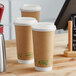 A couple of EcoChoice brown paper cups sitting on a table next to two cups of coffee.