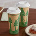 Two EcoChoice paper coffee cups with a tree print on the table with a plate of pastries.