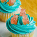 A cupcake with blue frosting and Albanese Pink Grapefruit Gummi Bears on top.