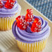 A cupcake with purple frosting and Albanese Wild Cherry Gummi Bears on top.