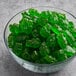 A bowl of Albanese Green Apple Gummi Bears on a table.